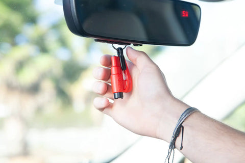 Hand holding 2 In 1 Emergency Car Escape Tool Keychain Hammer With Seatbelt Cutter And Window Breaker, Compact Red Lifesaver