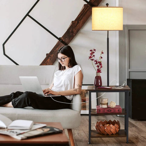 Woman using laptop next to End Table With Built In Lamp And USB Type C Port, Narrow Nightstand With Storage Shelf, Rustic Wood Grain