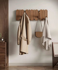 Walnut Wood Coat Rack Wall Mount With Eight Retractable Hangers And Two Dedicated Key Hooks displayed holding a coat and bag.