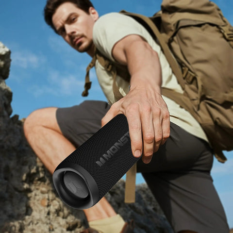 Person holding 60W Outdoor Bluetooth Speaker With IPX8 Waterproof while hiking, showcasing rugged build and portability