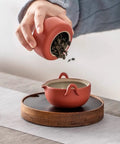 Elevate Your Kitchen Stash With These Top Shelf Ceramic Tea Canisters Featuring Snug Wooden Lids And Durable Porcelain Jars Perfect For Keeping Coffee Beans Sugar Or Salt Fresh As Ever Set Of 4 being used to pour tea.