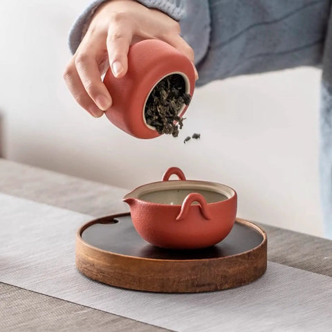 Elevate Your Kitchen Stash With These Top Shelf Ceramic Tea Canisters Featuring Snug Wooden Lids And Durable Porcelain Jars Perfect For Keeping Coffee Beans Sugar Or Salt Fresh As Ever Set Of 4 being used to pour tea.