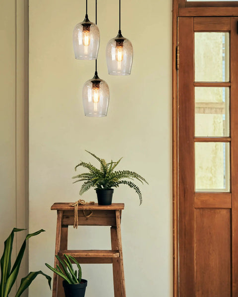 Three Light Teardrop Glass Pendant Chandelier With Hand Blown Seeded Bubbles illuminating rustic interior with plants