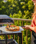 Perforated Aluminum Pizza Peel 12 Inch With Long Handle Lightweight Rectangle Turning Spatula Paddle For Oven Transfer in use outdoors