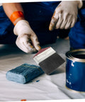 Workhorse Pro Grade Deck Stain Brush with ergonomic red handle beside paint can and gloves