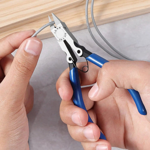 Hands using precision flush cutters and wire cutters for electronics and DIY projects on a wire, close-up view of the pliers.