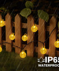 Solar String Lights For Outdoor 20Ft 30 LED Crystal Globe Fairy Lights Warm White With 8 Lighting Modes on wooden fence in rain