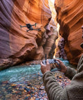 Person controlling Air 3S Drone With RC 2 Fly More Bundle For Travel And Content Creation, Dual 4K Cameras in scenic canyon.