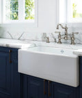 Edwardian Widespread Bridge Kitchen Faucet With Side Spray In Pure Unlacquered Brass 1.8 GPM displayed on a stylish marble countertop.