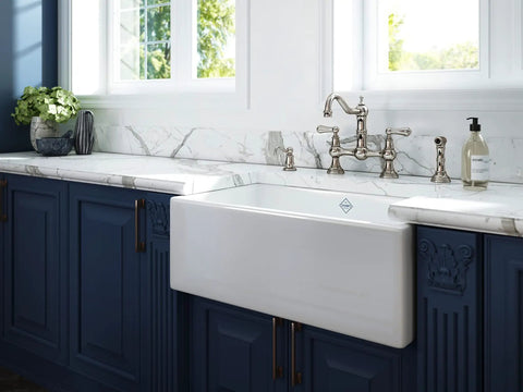 Edwardian Widespread Bridge Kitchen Faucet With Side Spray In Pure Unlacquered Brass 1.8 GPM displayed on a stylish marble countertop.