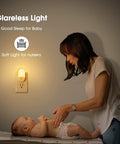 Woman caring for baby with Two Pack LED Night Lights Plugs Into Wall, Dimmable With Light Sensor, Auto On Off, 3000K soft white.