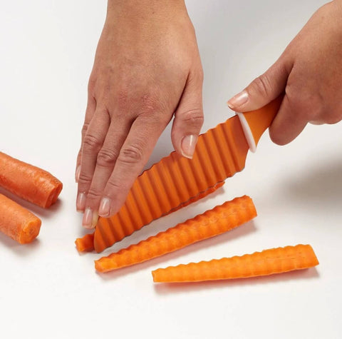 Orange plastic crinkle-cut knife for vegetables with a wavy blade used to slice carrot sticks.