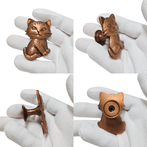 Hella Adorable 3D Sitting Cat Cabinet Knobs Four Pack Vintage Metal Drawer Pulls For Kitchen Cabinetry Upgrades With Embossed Fur Texture And A Super Chill Vibe To Liven Up Your House Today, bronze cat shape knob held in gloved hand.