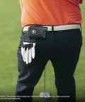 Golfer wearing heavy duty steel belt clip for magnetic golf rangefinders and accessories on white belt.