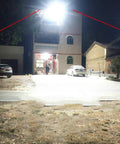 Hella Bright 10000W Solar Street Light With Remote Control IP65 Waterproof Dusk To Dawn Outdoor Flood Lamp illuminating a yard at night.
