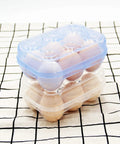 Stacked blue and clear Six Grid Egg Storage Box For Refrigerator And Camping with eggs on a checkered cloth.