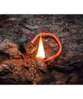 TinderZIP Zipper Pull Fire Starter With Built In Tinder igniting on a log, showcasing its ability for quick sparks in outdoor conditions.