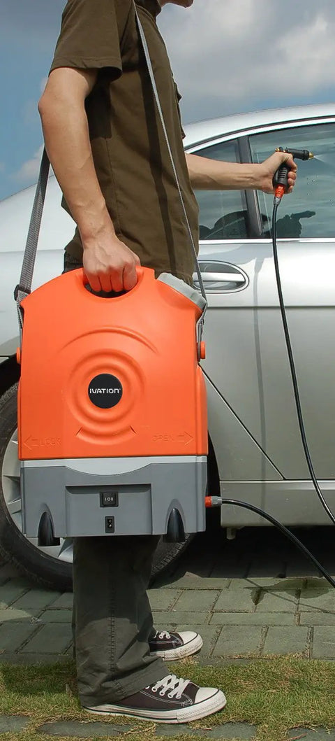 Man holding On The Go Portable Spray Washer With Built In Water Tank, Rechargeable Battery Or Car Or Home Plug, next to car