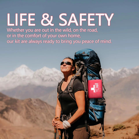 Red first-aid kit attached to a blue hiking backpack worn by a hiker in a mountainous landscape.