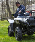 Man on ATV with Beefy ATV Broadcast Spreader With Rain Cover, 100 Pound Capacity Poly Hopper, Rear Rack Mount, on grassy lawn