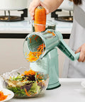 Using Rotary Cheese Grater Hand Crank 5 In 1 Mandoline Slicer With 5 Stainless Steel Blades to shred carrots into a salad bowl.