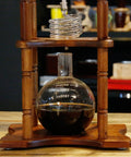 Slick Cold Brew Coffee Tower Featuring A Reliable Ice Drip System For Bold Flavor Kick Holds A Humongous 3000ML Glass Jar Settled On A Raw Brown Wood Stand.