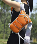 Mens Hydration Running Vest With Built In Water Bladder Ultralight Hiking Backpack For Running Cycling And Outdoor Gear Reflective Safety Strips Orange One Size in use outdoors by a woman