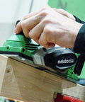 Hand using 18V MultiVolt Cordless Hand Planer With Three And A Quarter Inch Cutting Width Tool Only No Battery 16,000 RPM No Load Speed 5/64 Inch Planing Depth Great For Quick Wood Surfaces And Trim Projects on wood
