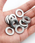 Close-up of stainless steel flat washers in a hand; M12, inner 12mm, outer 24mm, 2.5mm thick, 50 pieces