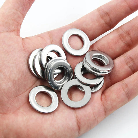 Close-up of stainless steel flat washers in a hand; M12, inner 12mm, outer 24mm, 2.5mm thick, 50 pieces