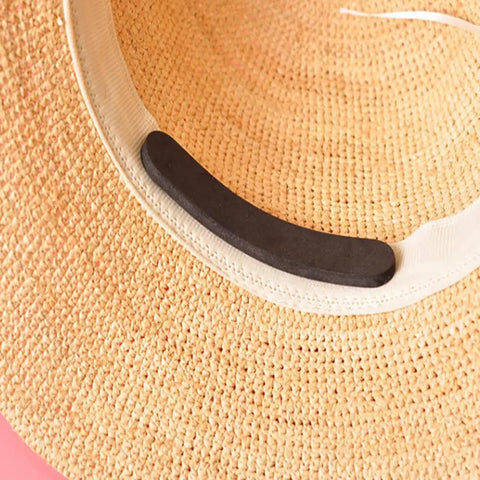 Black reducer strip from 30-Piece Hat Size Reducer Tape Set For Hats And Caps placed inside straw hat, showing application.