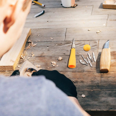 Close-up of 12 Pack Linoleum Cutter Kit for Block Printing and Linocut with yellow handle and blades on wooden table.
