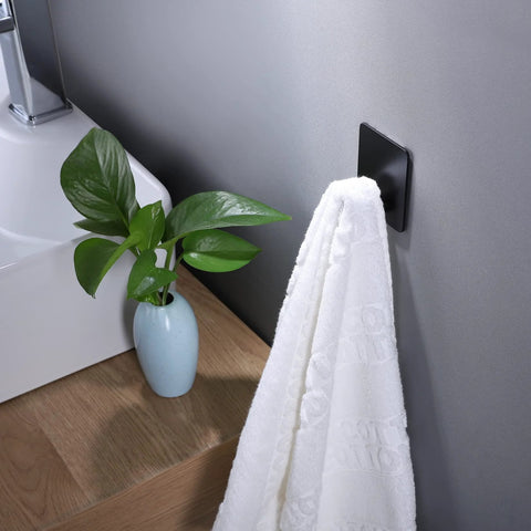 Matte black Adhesive Hooks 4 Pack Towel And Coat Hooks For Wall Mounting Stick On Bathroom Kitchen next to a towel and plant