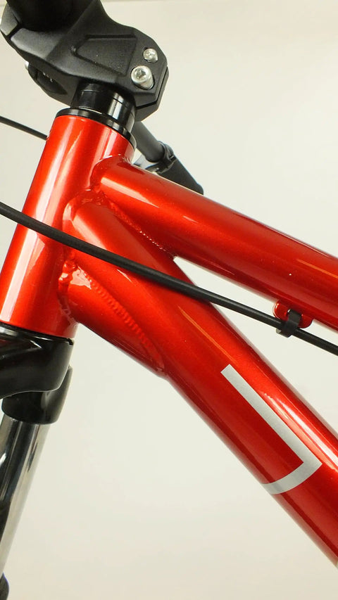 Close-up of Salire SJ-50 Dirt Jumper Bike With Disc Brakes And 26 Inch Wheels, red steel frame detail and suspension fork.