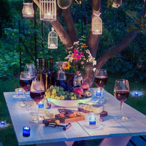 Outdoor evening setting with Blue White LED Flameless Candles With Realistic Flame Effect Battery Powered Votive Lights on decorated table.