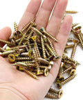 Hand holding a pile of golden screws with flat heads and sharp tips, suitable for various construction applications.