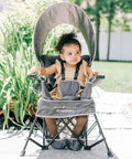 Child sitting in Go With Me Venture Portable Toddler Chair On The Go With Sun Canopy For Indoor And Outdoor Use, Grey, outdoors