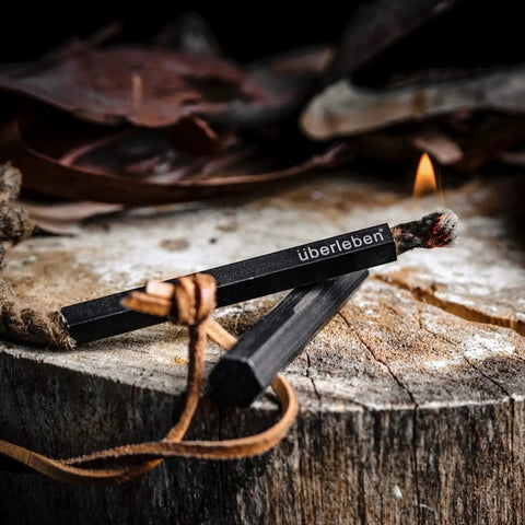 All Weather Fire Starter Kit With Paraffin Wax Infused Hemp Wicks And Aluminum Bellow Sleeve on wood surface with flames.