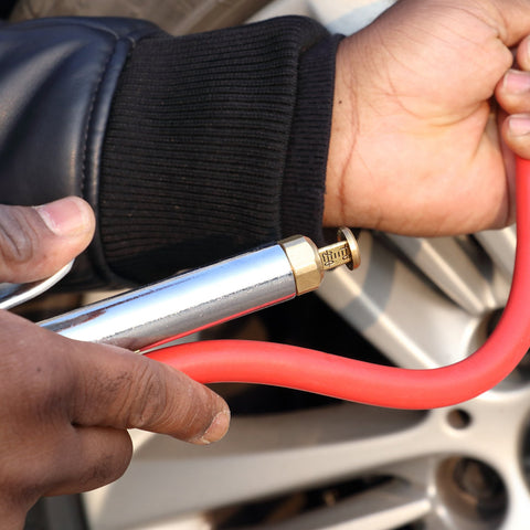 Close-up of hands using the Bayonet Style Tire Inflator Gauge with 12 inch heavy duty air hose and straight head chuck on a car tire