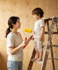 Woman on ladder playfully holding a yellow roller from 10 Pack 4 Inch Foam Paint Roller Kit With Heavy Duty Spring Handles For Smooth Rollouts And Clean Edge Trimming Ideal For Latex Or Oil Based Coatings On Interior Walls.