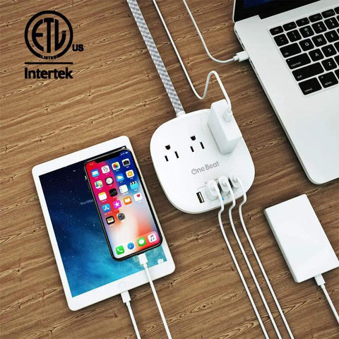 Desktop Power Strip With Three Outlets And Four USB Ports No Brainer Charging For All Your Gadgets Fast 4.5 Amp USB Quick Charge Flat Plug 5 Ft Braided Extension Cord Great For Cruise Ship Travel And Home Office ETL Listed in use with devices connected on wooden desk.