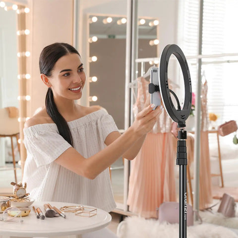Woman using Extendable 6.23ft Aluminum Light Stand For Photography with smartphone in dressing room setting.