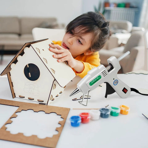 Child using Dope Mini Hot Glue Gun Kit With 30 Glue Sticks, Fast Heating Hot Melt Gun For School Projects, Crafts, DIY Arts And Quick Home Repairs, High Temp, Compact White Tool For Everyday Fixes to assemble a wooden birdhouse.