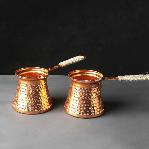 Side view of two copper Turkish coffee pots with dimpled surface, 300ml capacity, easy pour spout, open flame safe.