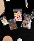 500 Pack Small Clear Resealable Plastic Bags With Four Size Options For Jewelry Candy Pills And More, Durable Reusable Poly Bags For Packaging Storage And Organization Grab And Go Ready with candies and dried fruits inside on black background.