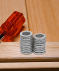 Set Of Twenty M10 Wedge Locking Washers Built Tough With Premium Manganese Steel stacked beside a red screwdriver on wood.