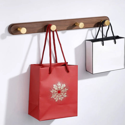 Rock Solid Wall Mounted Coat Rack With Five Hooks For Entryway And Bathroom holds red and white bags on a wooden wall mount.