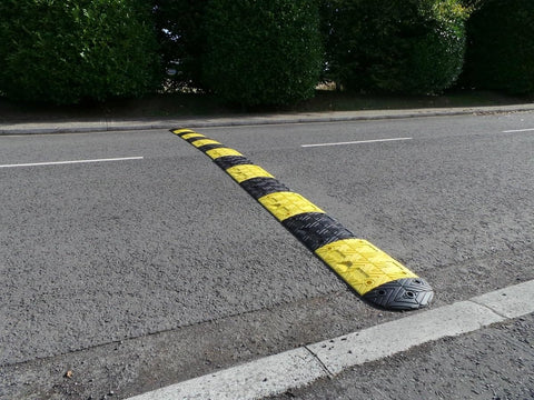 Eco XPT Speed Bump Kit With Cable Channel for Private Roads on Asphalt, showing black and yellow reflective modular design with mounting hardware.