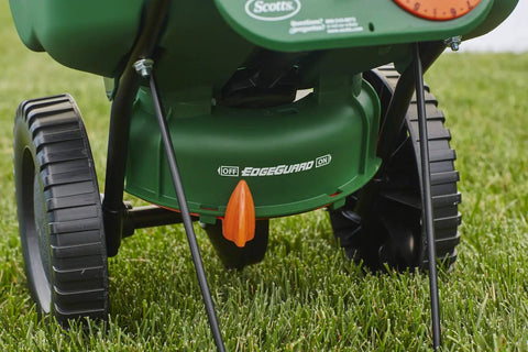 Edge Guard Mini Broadcast Spreader With Calibrated Settings And Wheels on grass, ideal for lawns up to 5,000 sq ft.