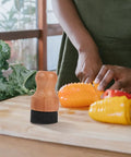 Straight Up Amazing Wooden Cutting Board Oil Brush And Built Tough Wood Wax Applicator Sponge on a kitchen counter with chopped vegetables.